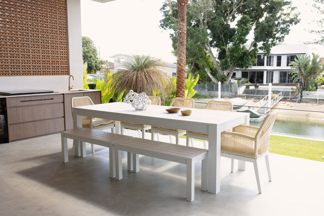 A patio with a comfortable outdoor sofa surrounded by potted plants and cushions